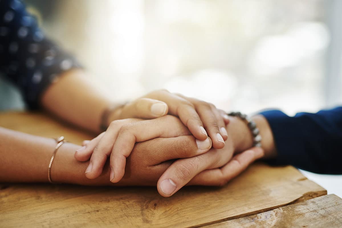 a woman laying her hands on top of another woman's hands to offer support