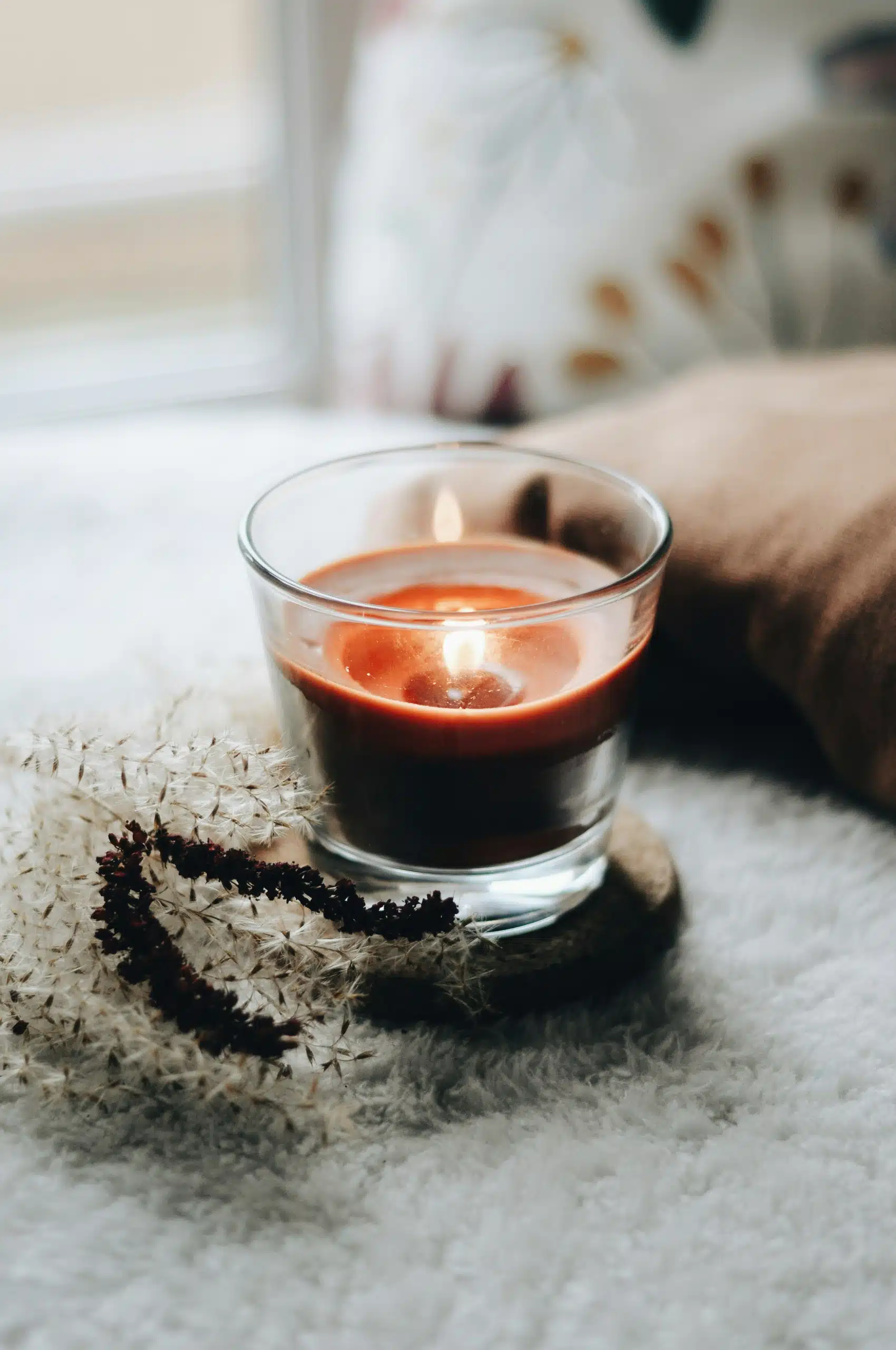 A single, relaxing candle in a peaceful room with natural light